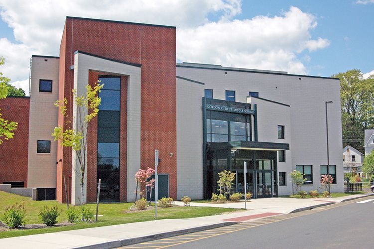A large building with a lot of windows is sitting on the side of the road.