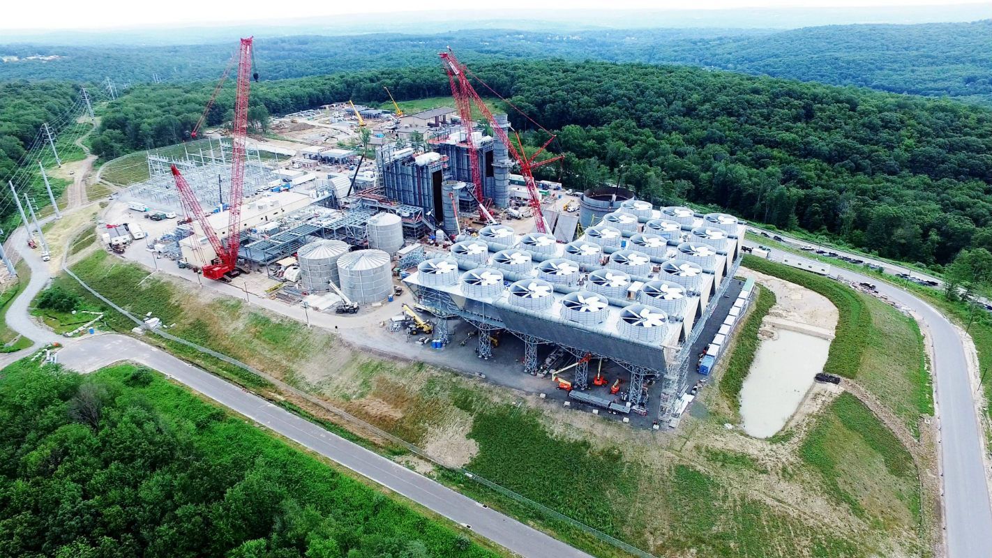 An aerial view of a large building under construction in the middle of a forest.