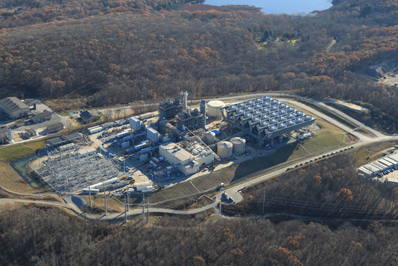 An aerial view of a power plant in the middle of a wooded area.