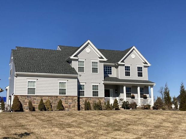 Teal two-story house with white trim, front porch, and gabled roof under a blue sky