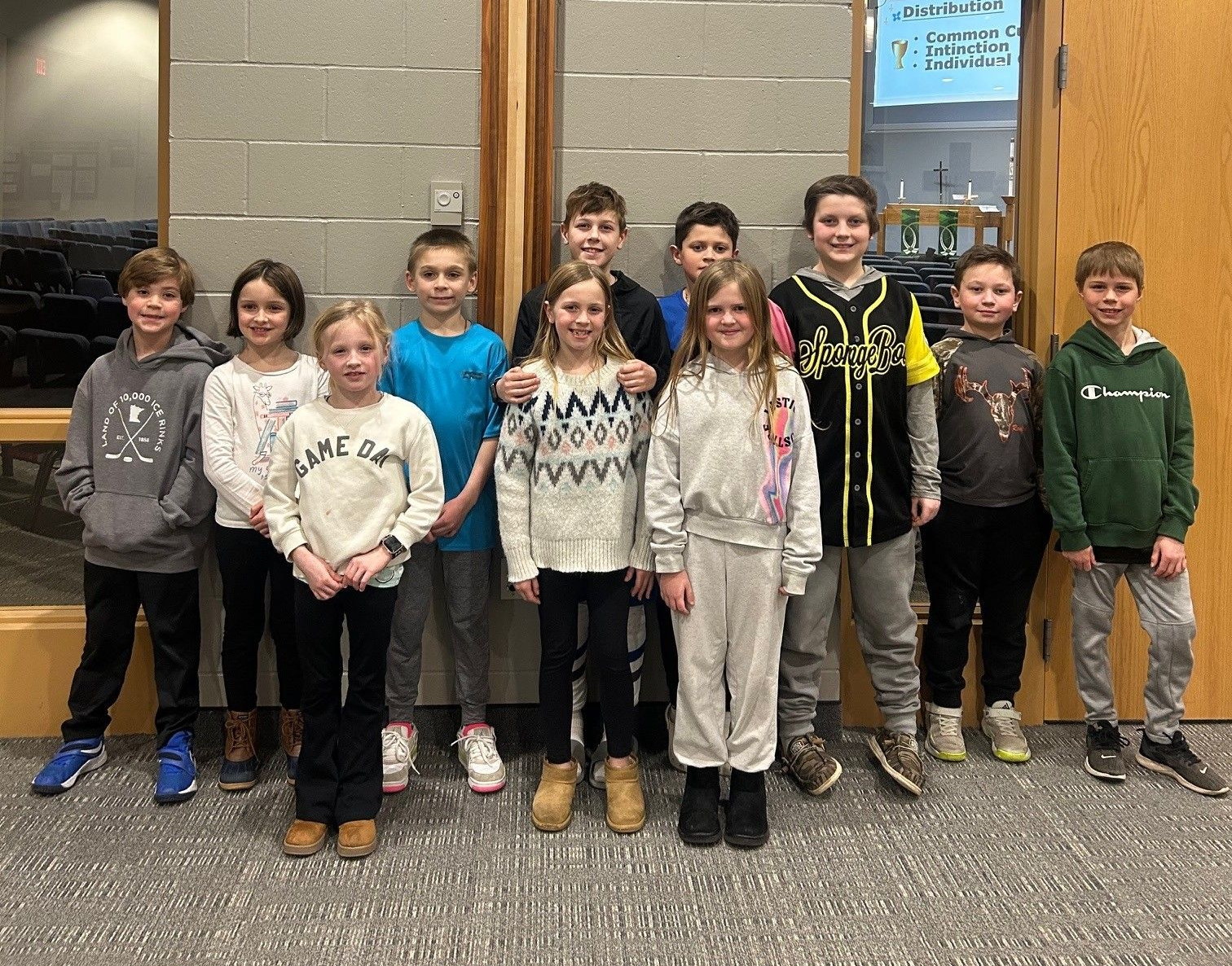 A group of children are posing for a picture in front of a screen that says clay and you are the putter