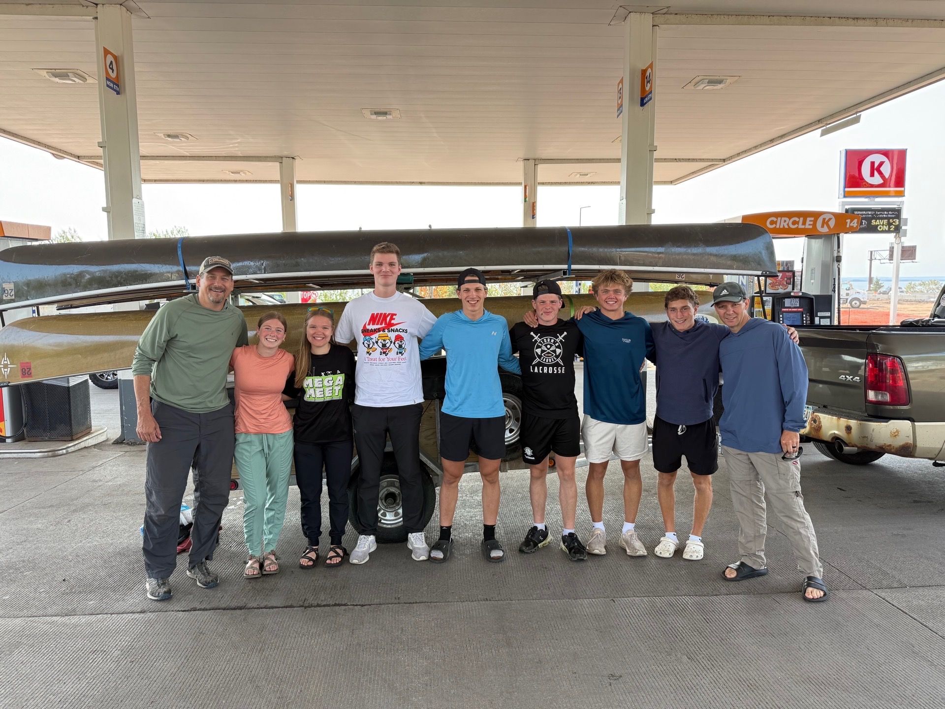 A group of people are posing for a picture in front of a canoe.