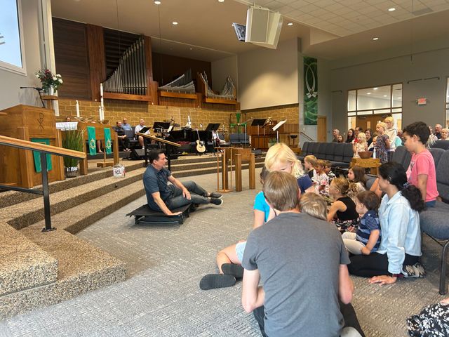 A man is kneeling down next to a little girl in a church.