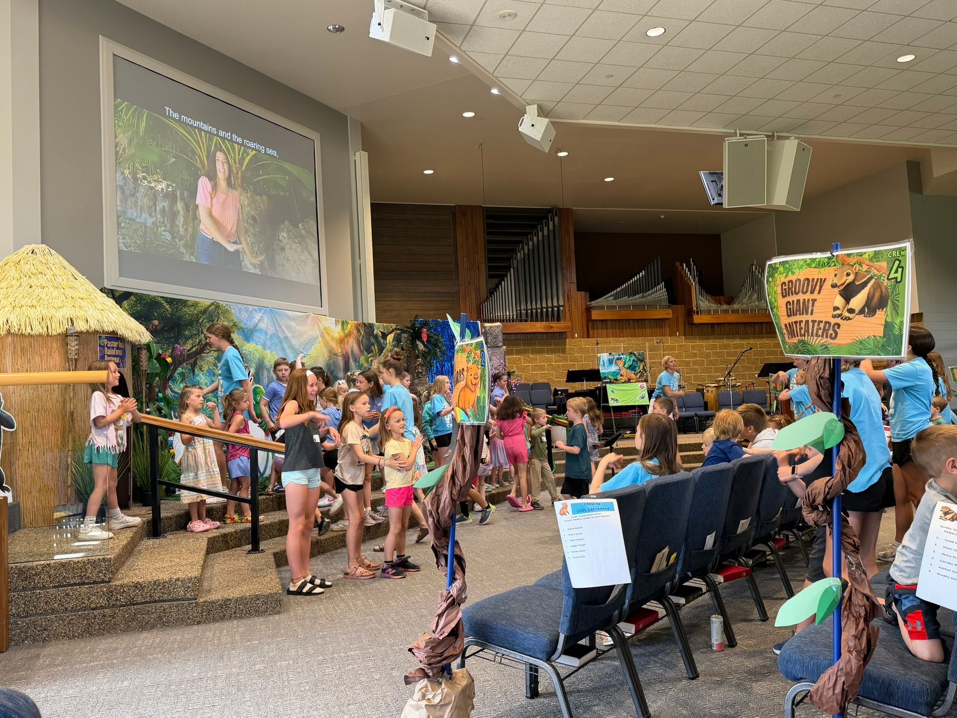 A group of people are sitting in front of a large screen that says vbs 2025.