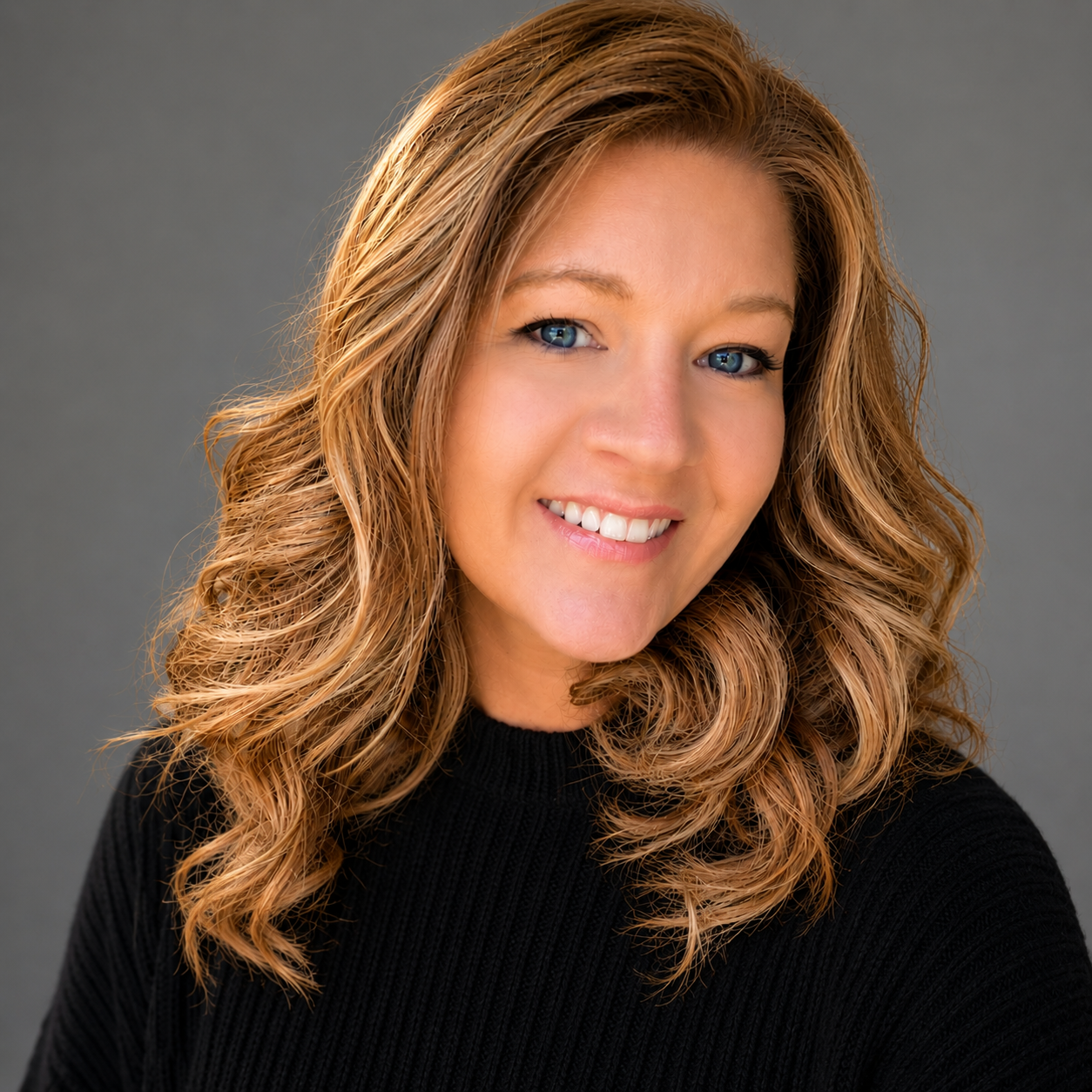 A woman in a black jacket is smiling for the camera.
