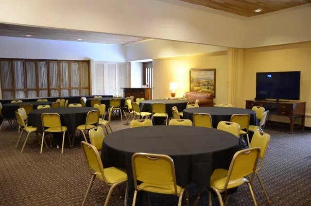 A room with tables and chairs and a flat screen tv