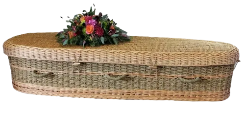Willow and seagrass woven green burial casket with a spray of flowers on top of it.
