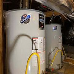 Two gray water heaters in a utility closet with yellow gas lines and exposed ductwork