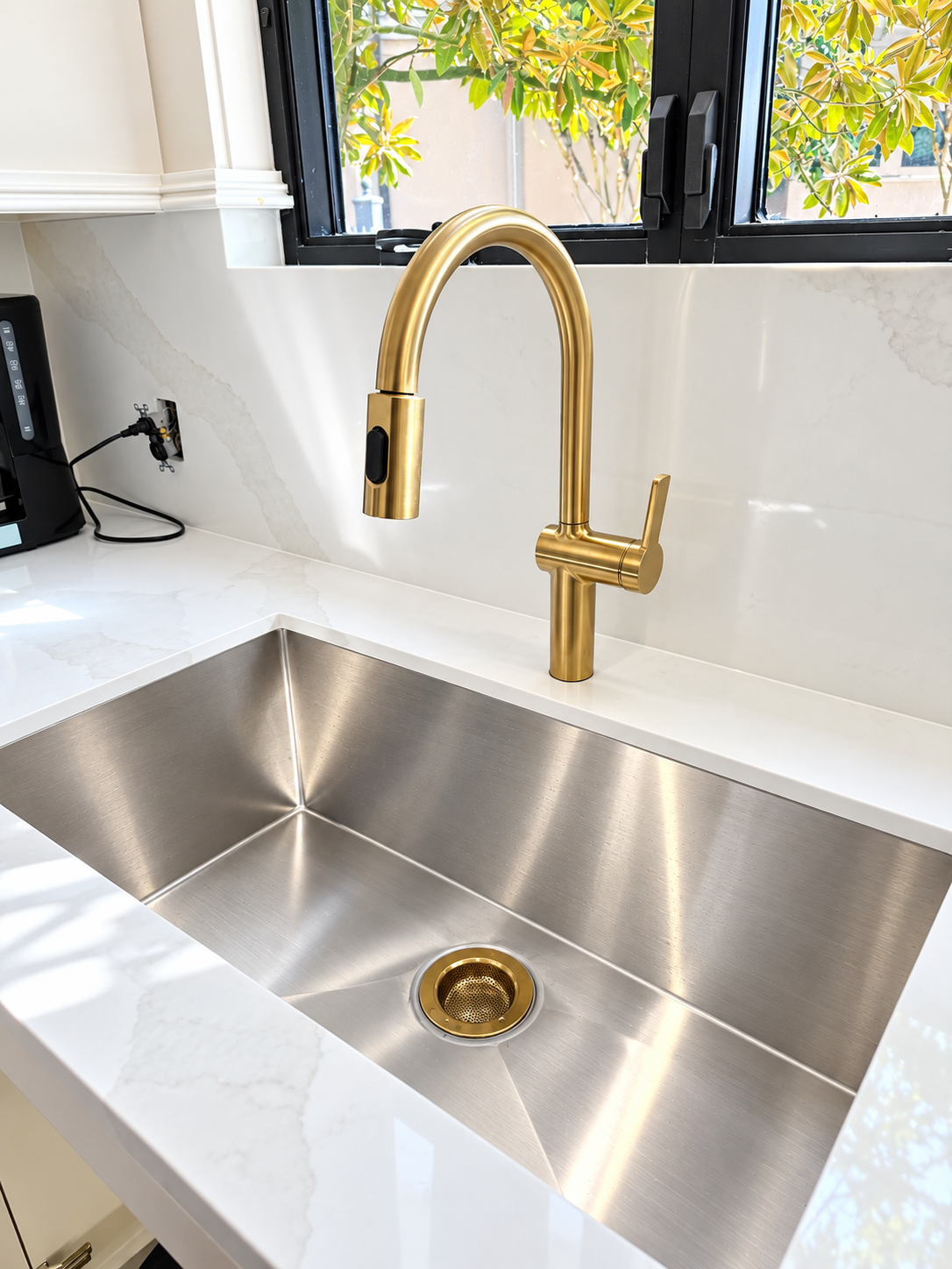 Chrome faucet over a round sink on a dark countertop in a gray tiled bathroom