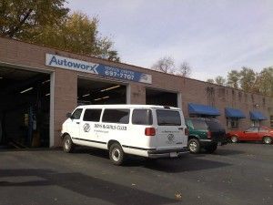 Auto repair shop with service vans parked outside under blue awnings | Autoworx