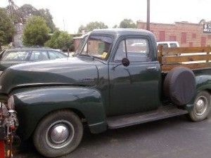 Dark green vintage pickup truck parked outdoors, side view | Autoworx