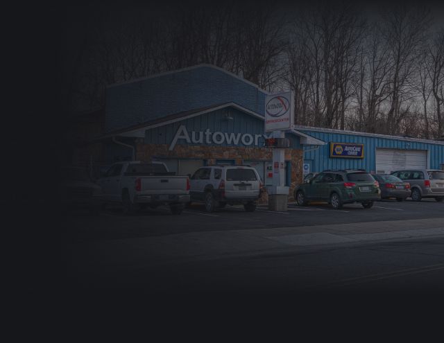 AutoWerks car dealership with parked vehicles outside a blue building on a cloudy day | Autoworx