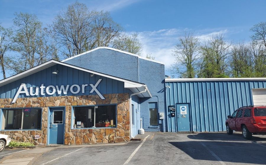 AutoworX auto shop exterior with blue siding, stone storefront, and a parked red SUV | Autoworx