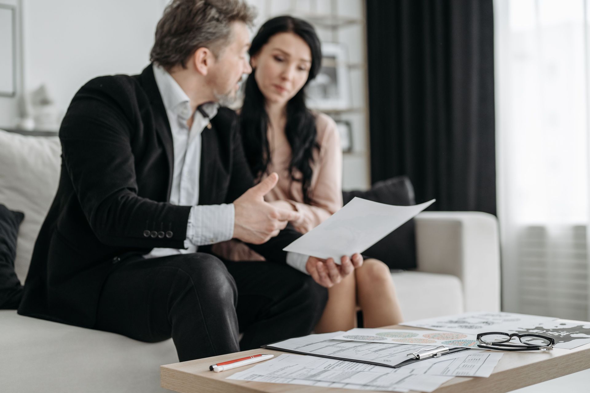 Two professionals reviewing documents on a sofa in a modern office lounge