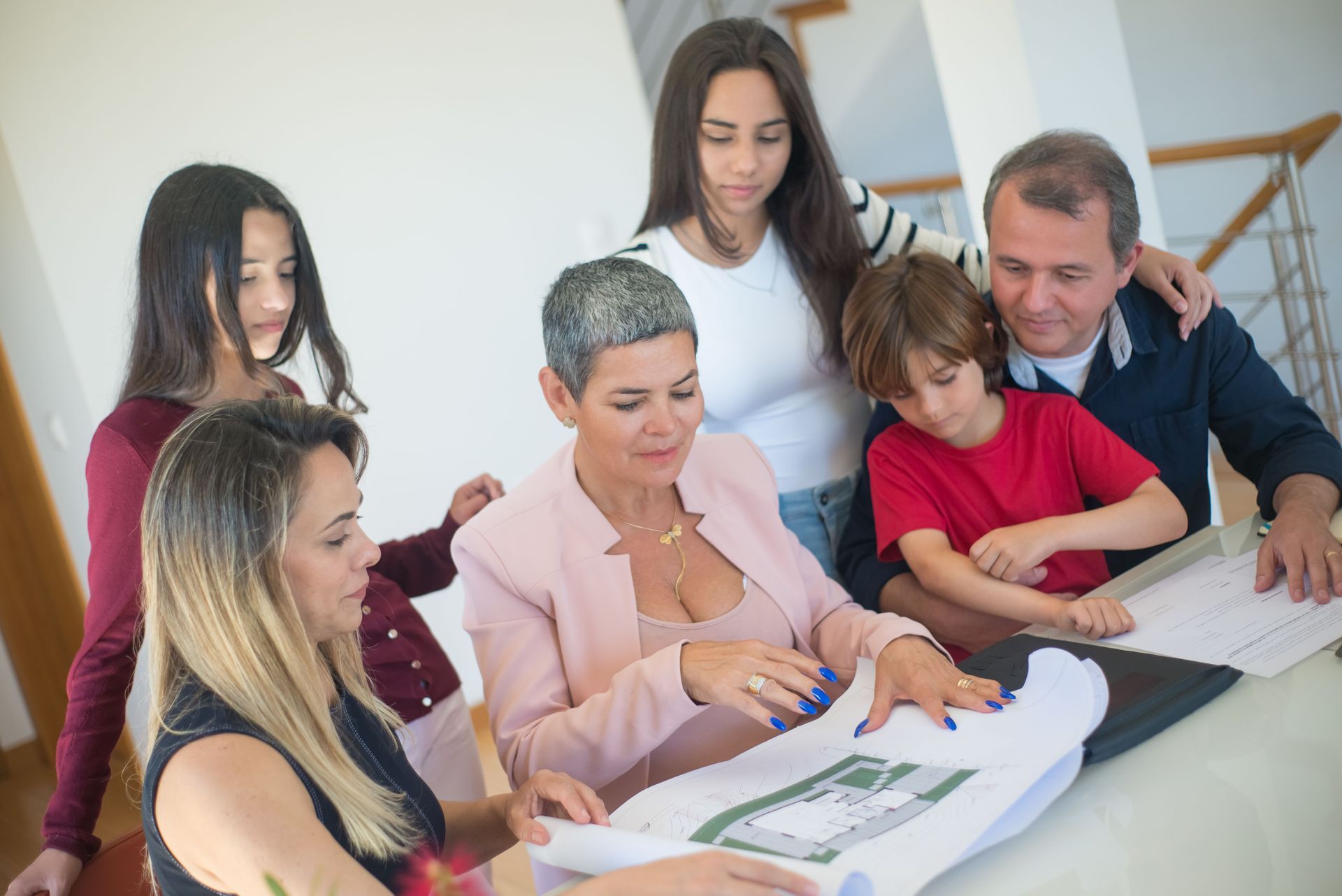 Group gathered around a table reviewing documents in a bright office, with one person pointing at a page.