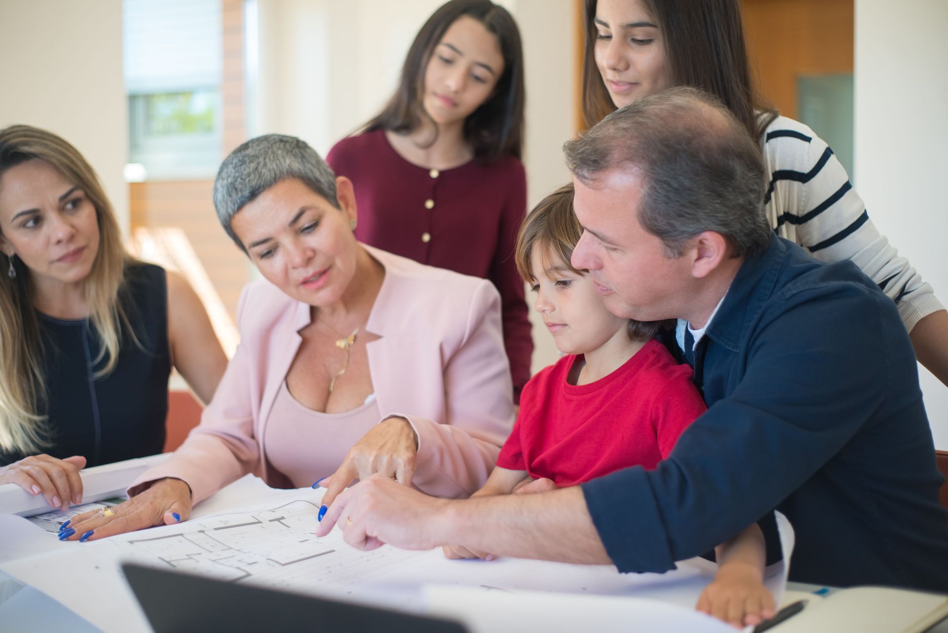 Group of people reviewing documents together at a table, pointing and discussing in a meeting room.