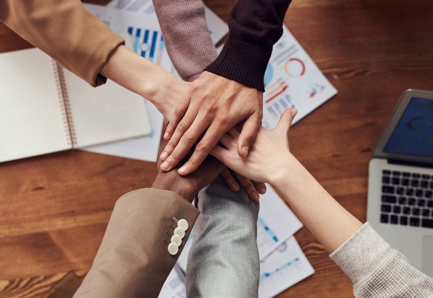 a group of people are putting their hands together .