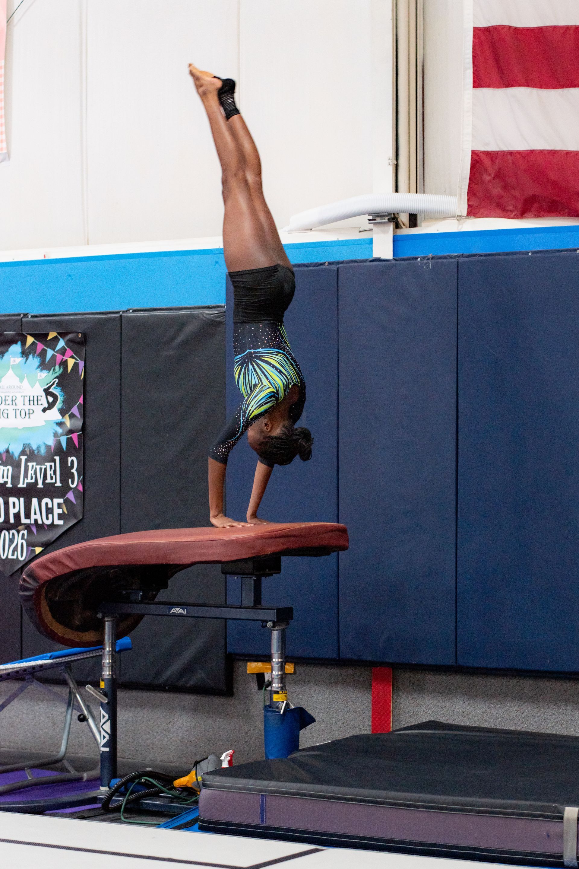Gymnast balancing on hands on a vault table in an indoor gymnastics gym