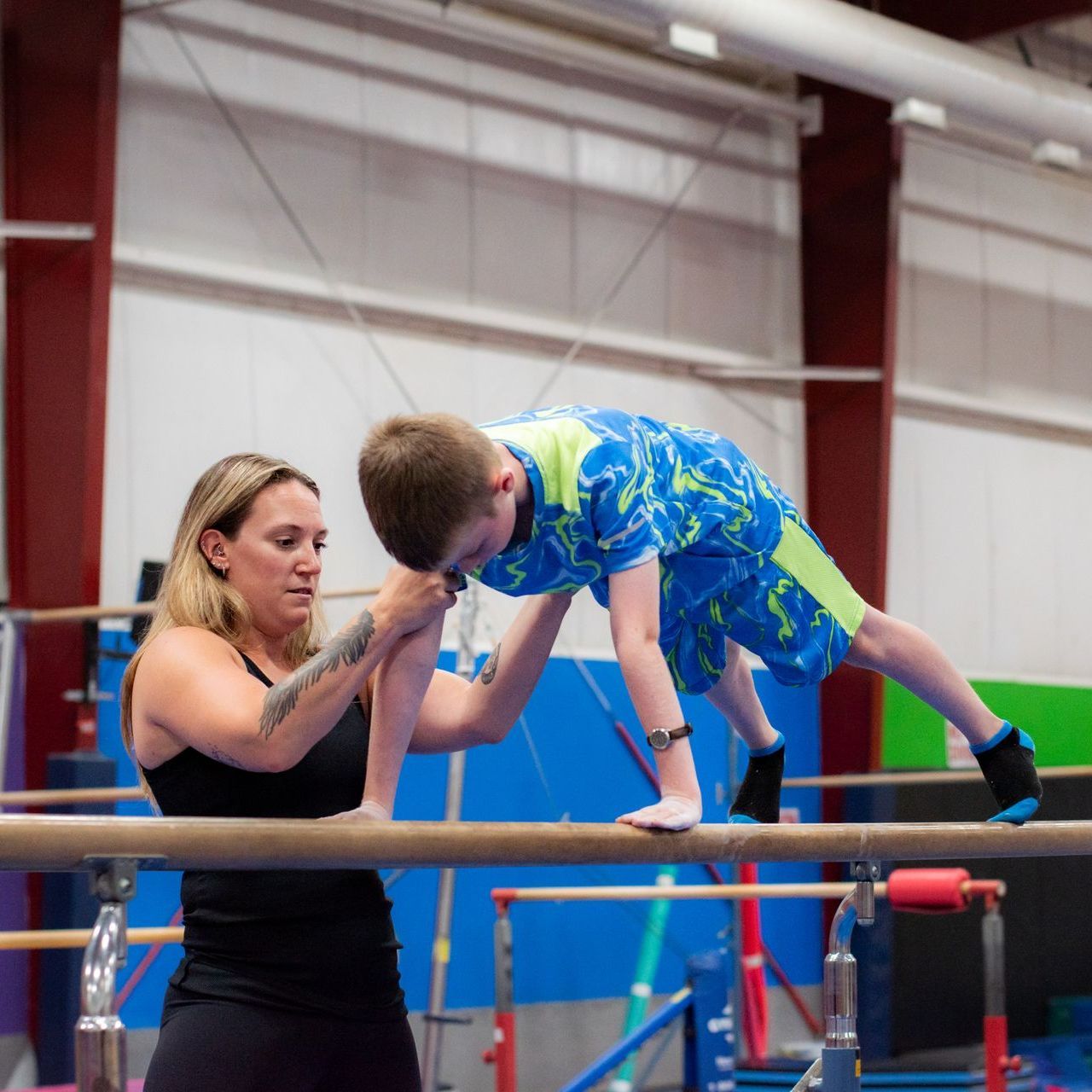 Coach spotting child on gymnastics bars in indoor gym