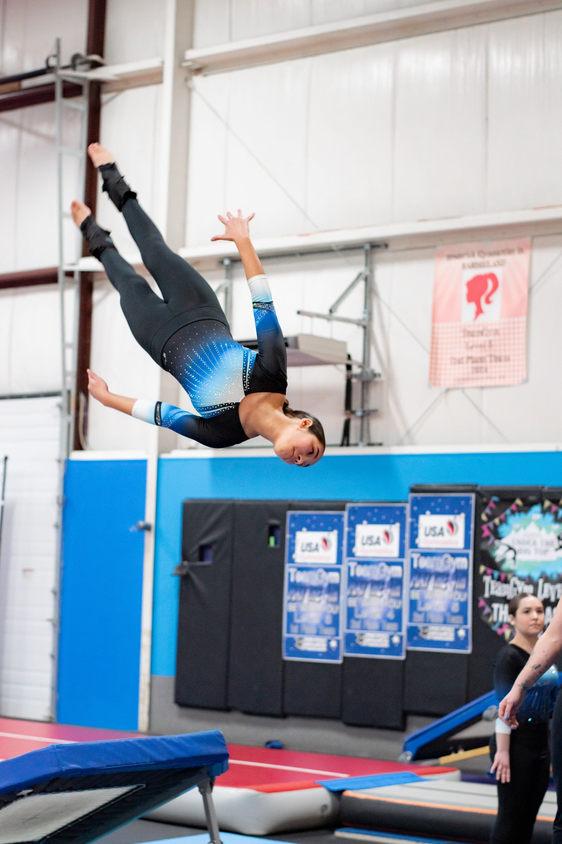 Gymnast flipping upside down on a trapeze in an indoor training gym