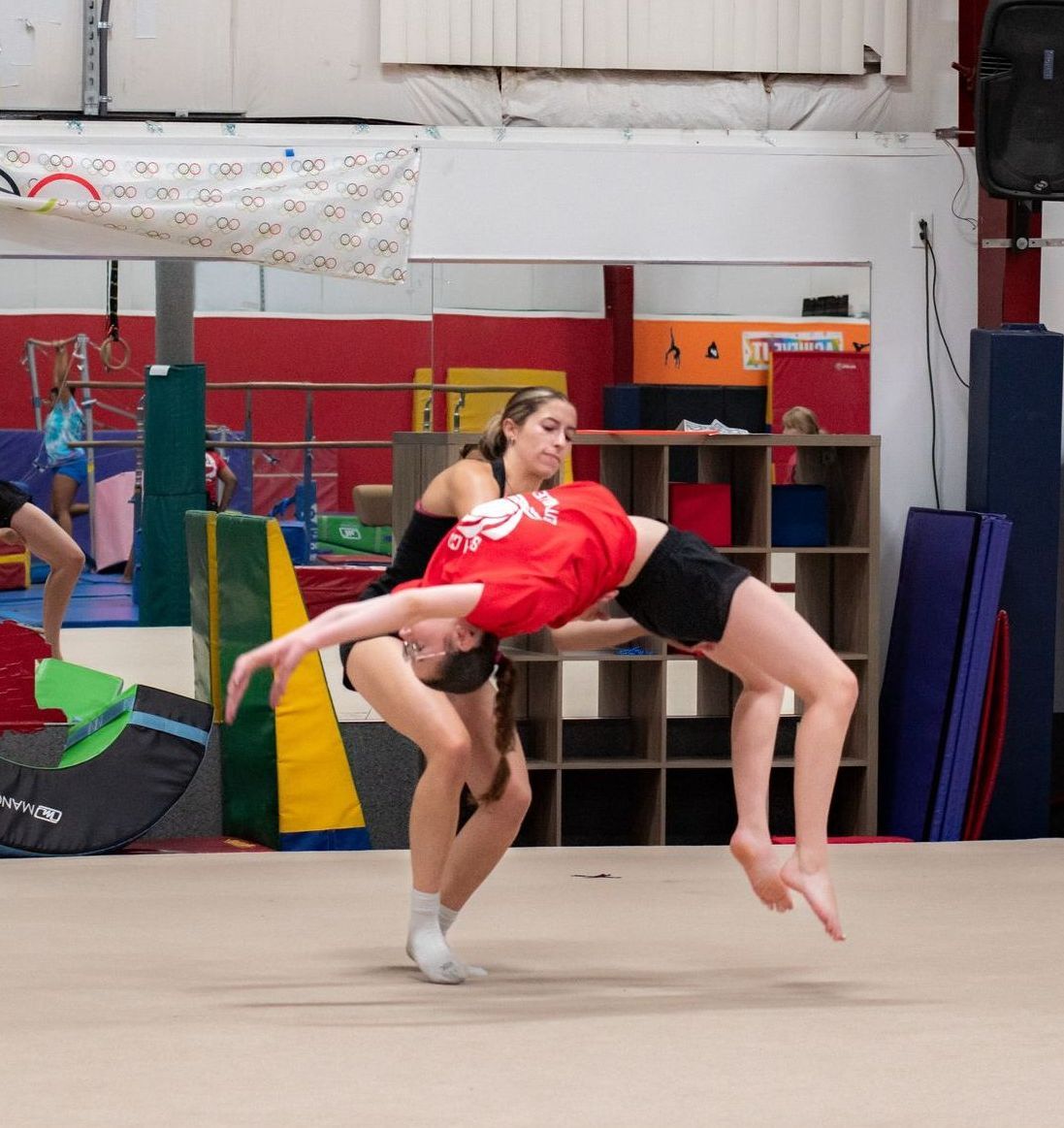Two gymnasts performing a lifted balance pose in a training gym