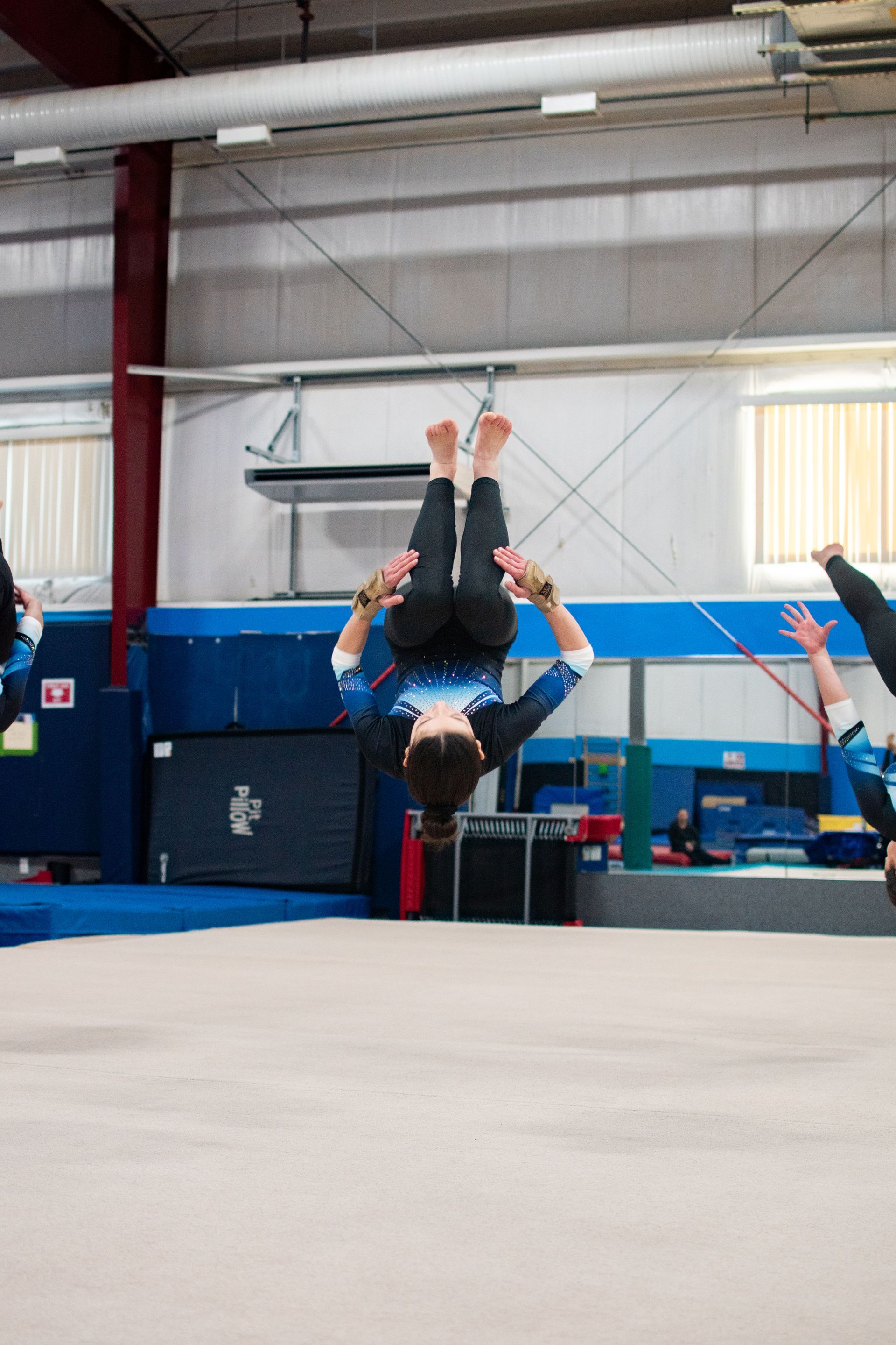 Person flipping upside down in a gym with blue padded walls and a spring floor