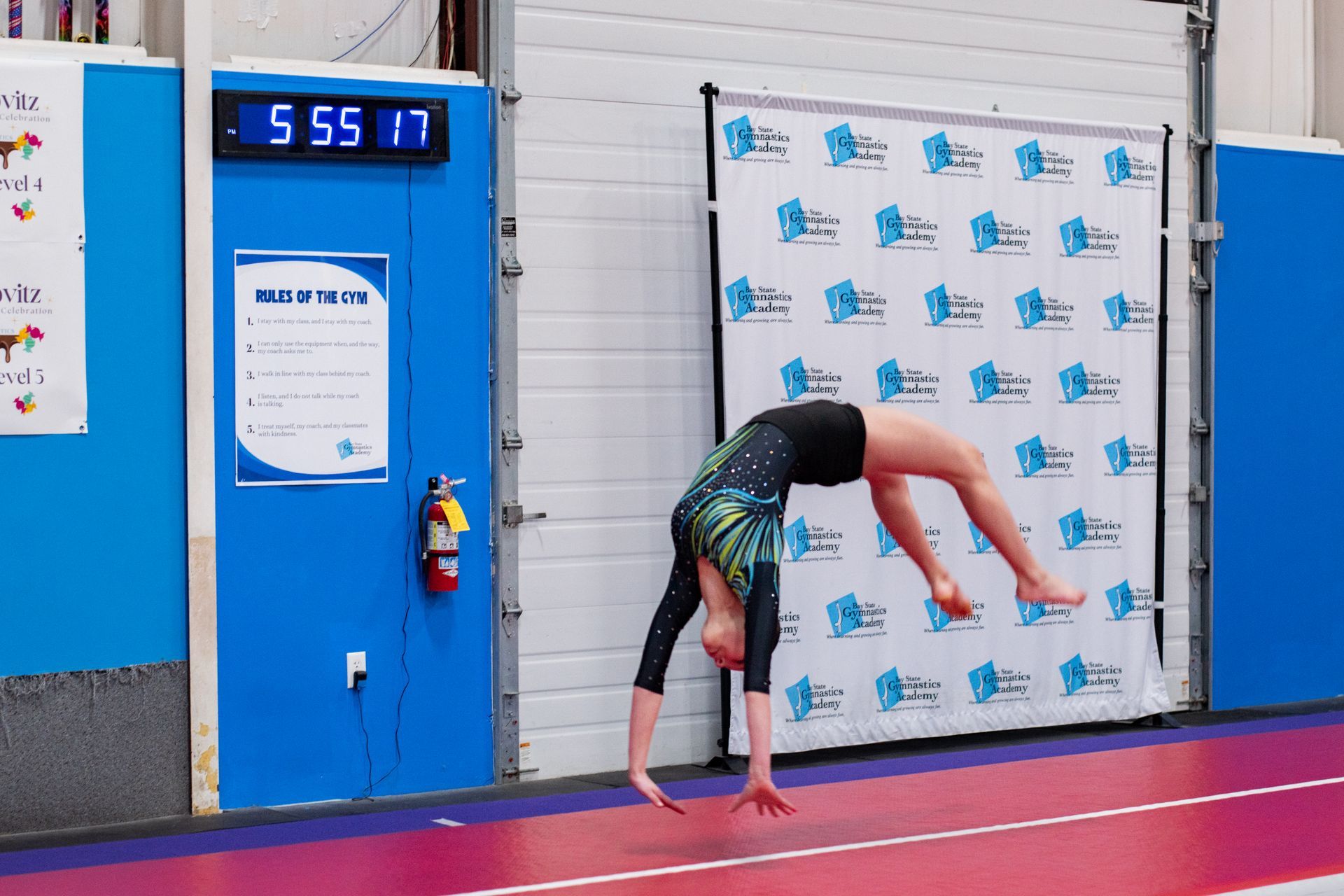 Gymnast doing a back walkover on a pink mat in an indoor gym