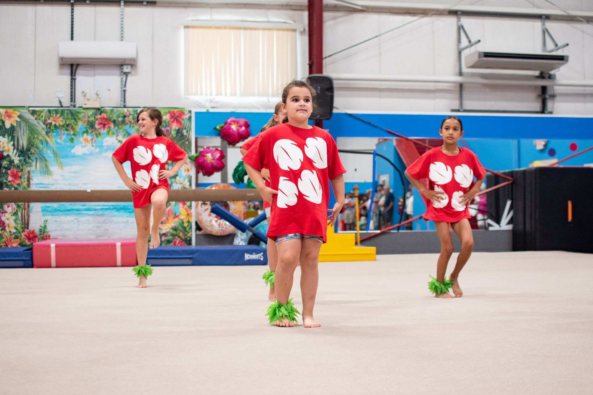 Gymnast performing a one-handed handstand on a spring floor in a training gym