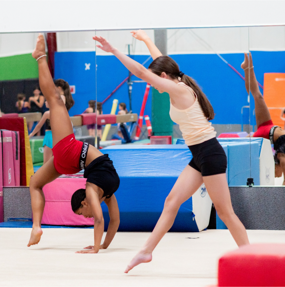 Gymnast performing a one-handed handstand on a spring floor in a training gym