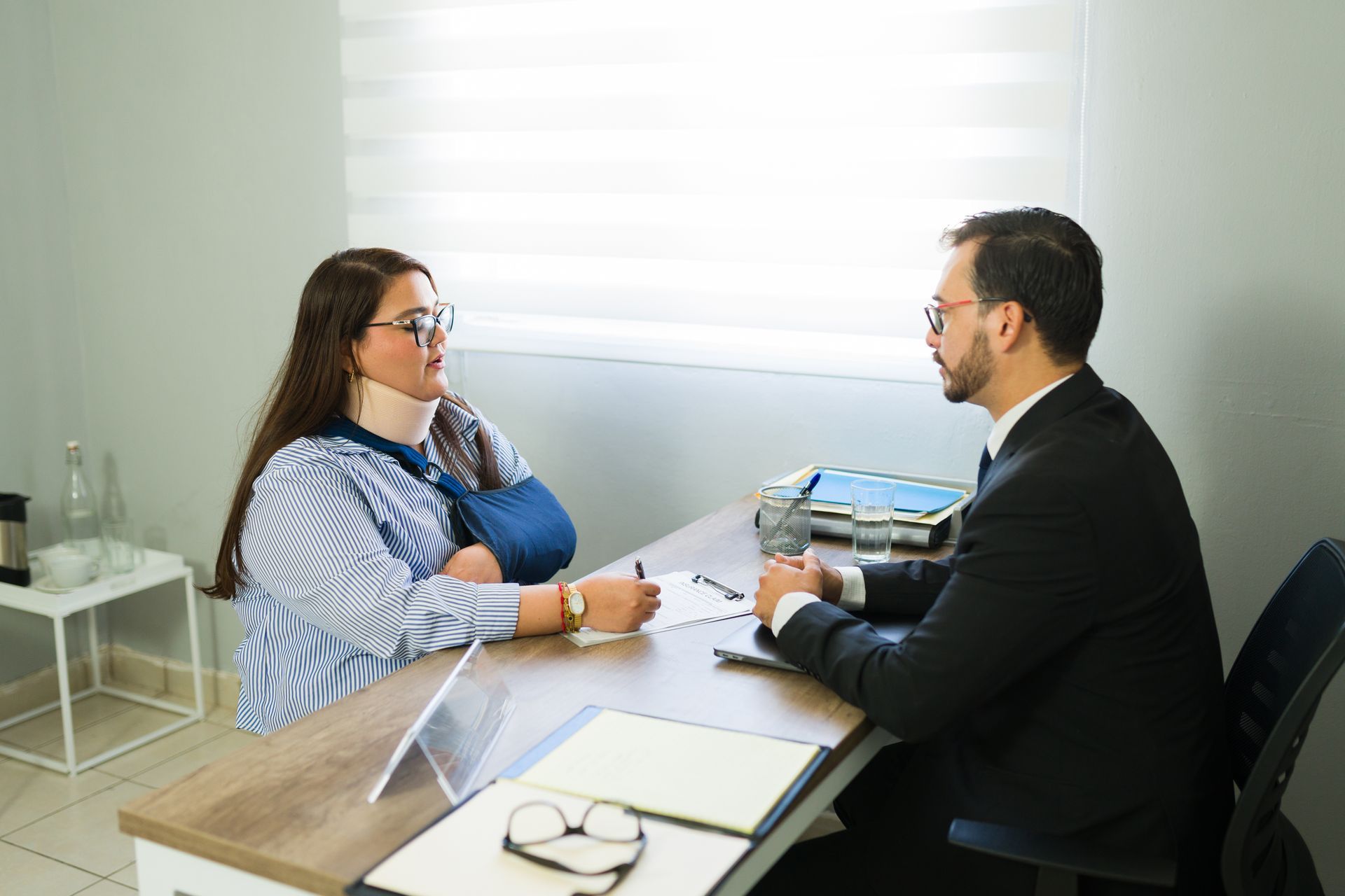 Woman with neck brace discussing legal claim with lawyer.