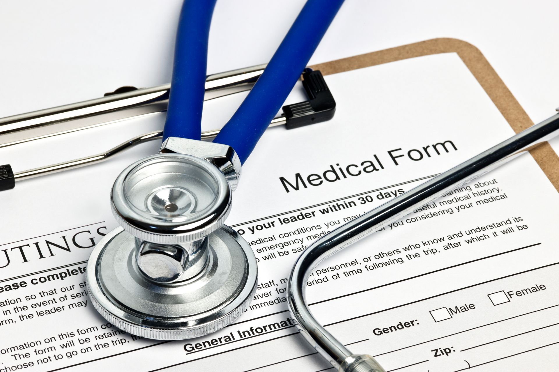 Blue stethoscope on a clipboard with a medical form.