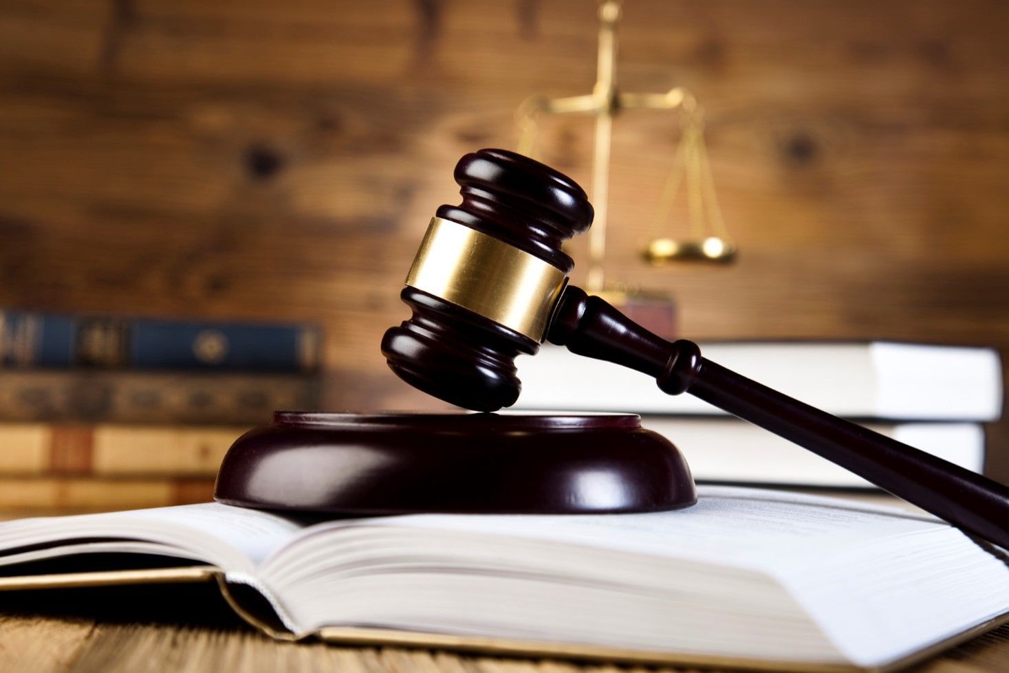 Gavel on open book, scales of justice and books in background.