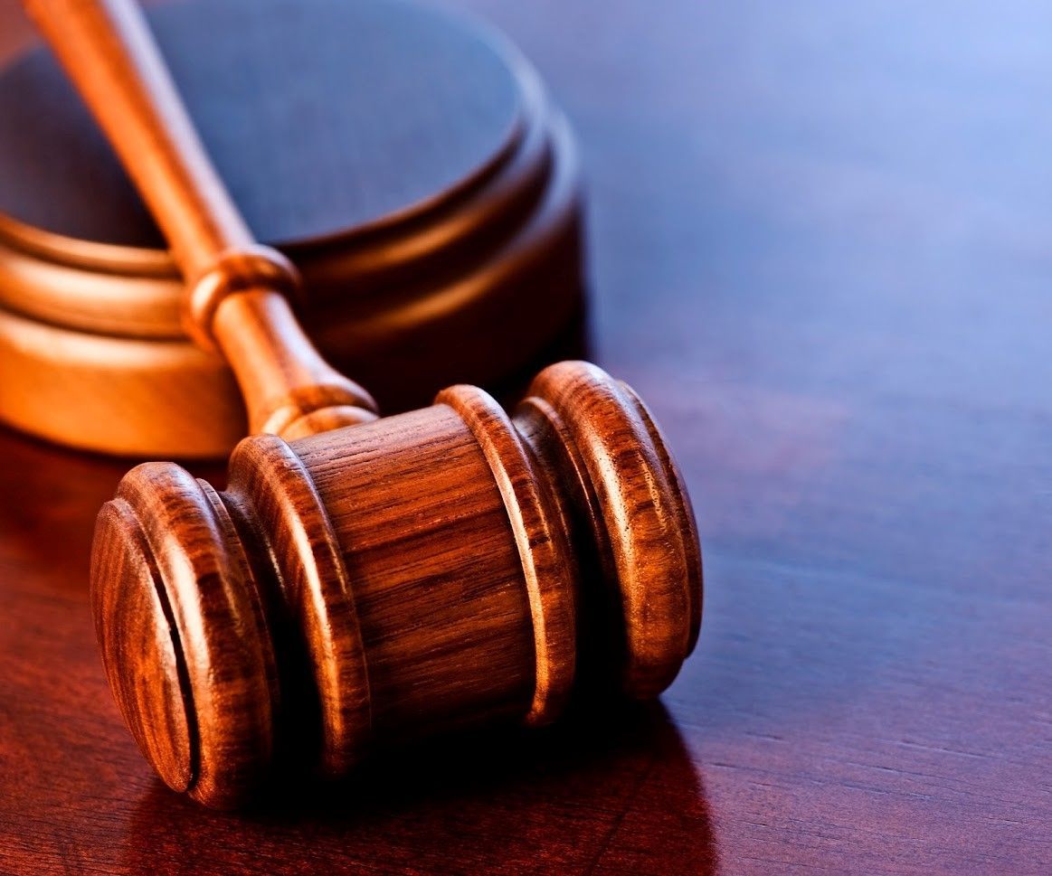 Wooden gavel resting on a wooden block, angled, with a shiny surface.