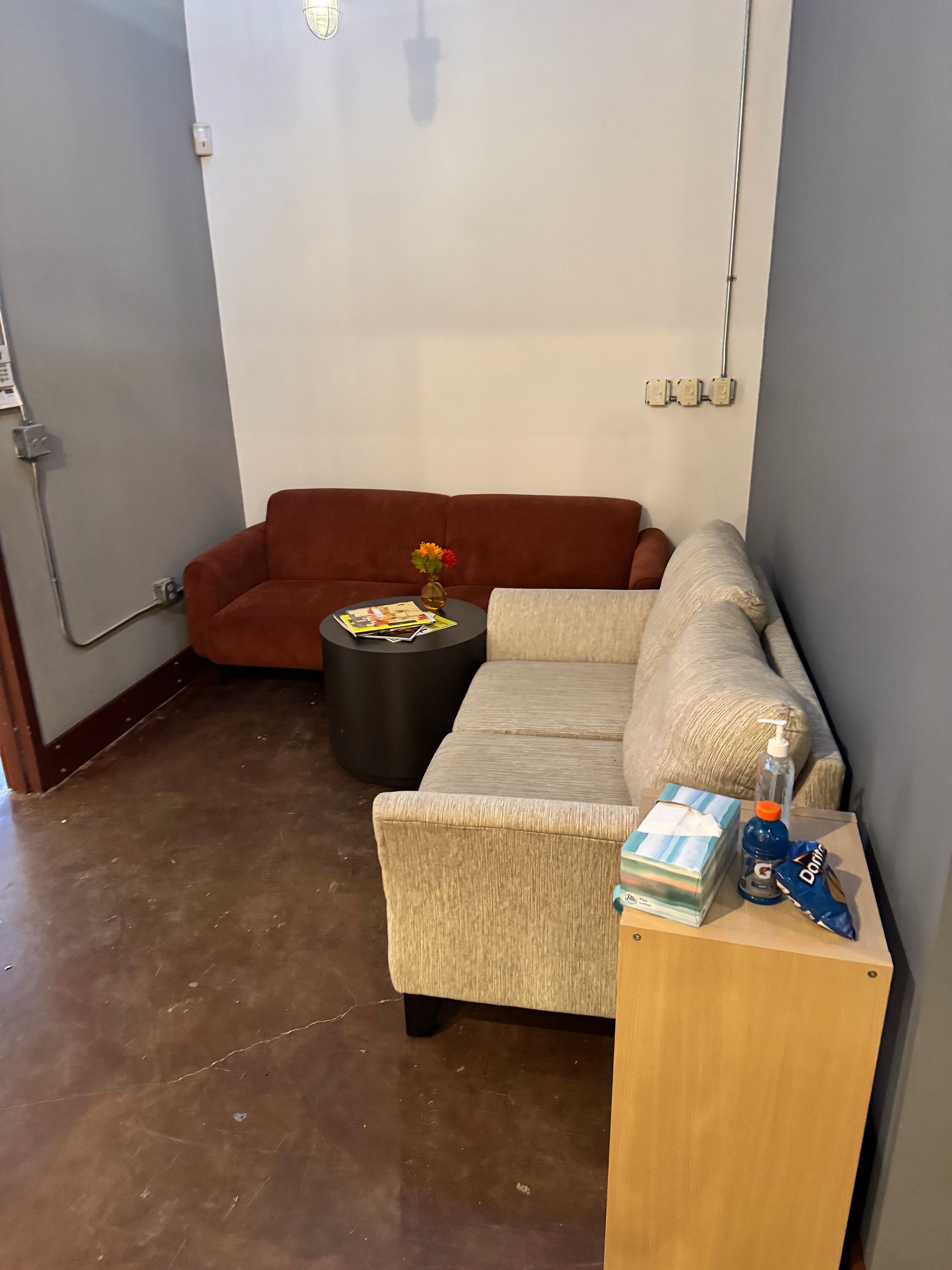 Small waiting area with two couches, round table, and a side table with items.