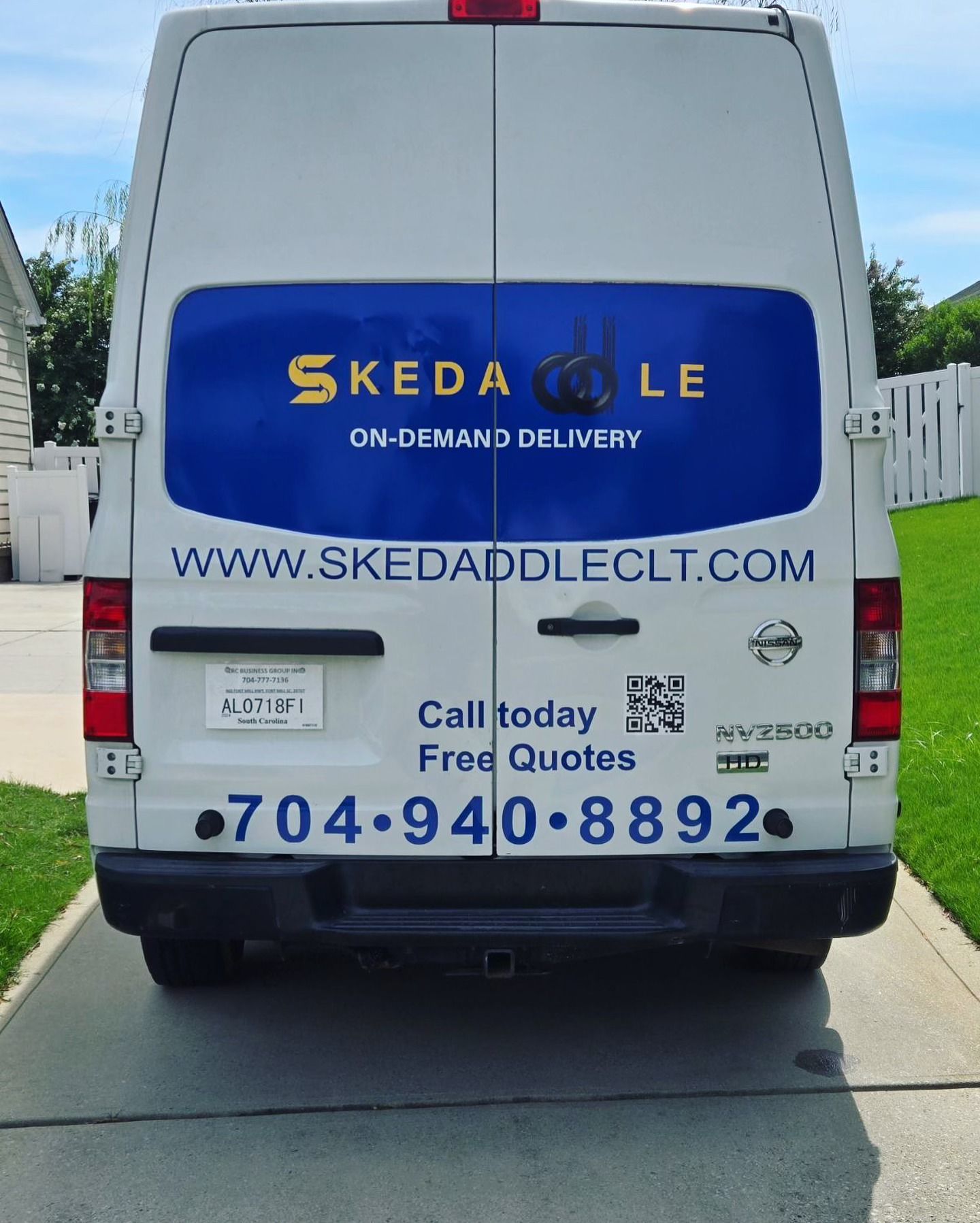 Rear view of a white delivery van with blue and gold lettering: 