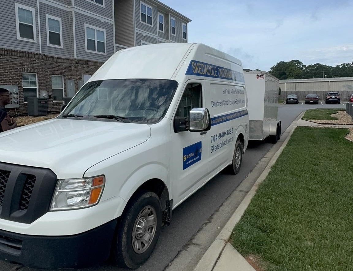 White van with trailer parked near a building. The van has blue and Chinese text on its side.