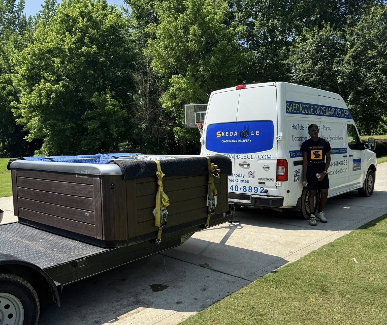 A hot tub on a trailer, attached to a white service van, man standing next to the van.