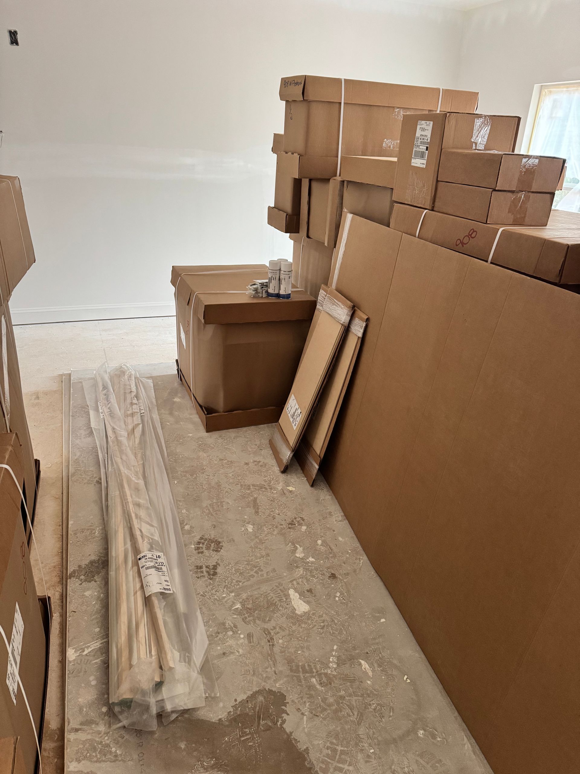 Boxes and building materials stacked in a room with a concrete floor.