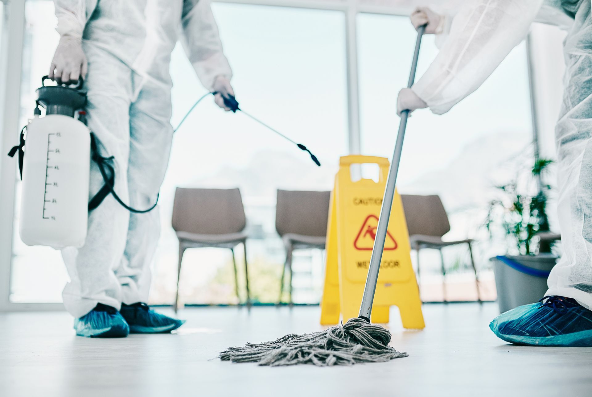 A group of people in protective suits are cleaning a room.