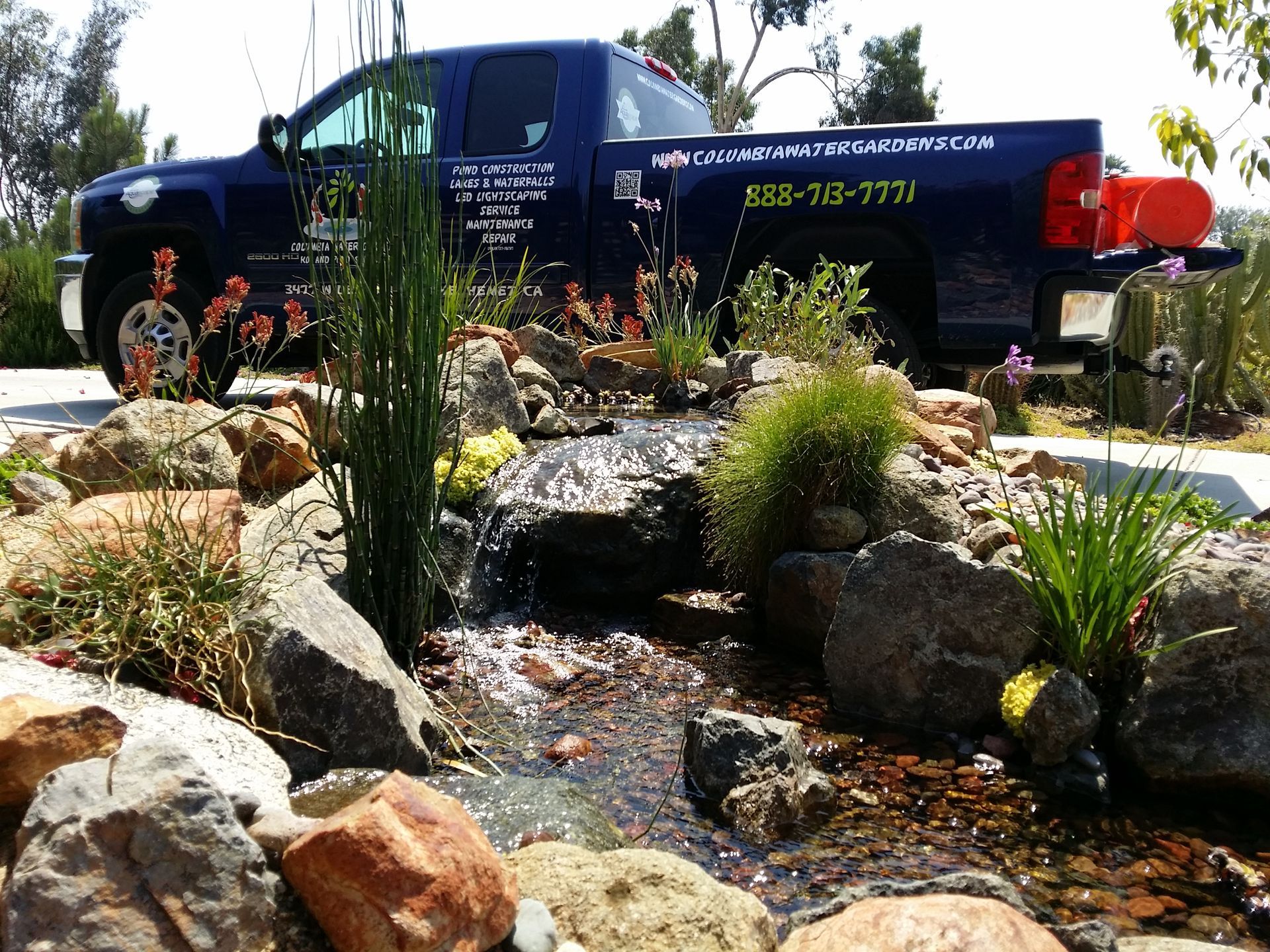 Water feature with waterfall and truck with company logo parked behind.