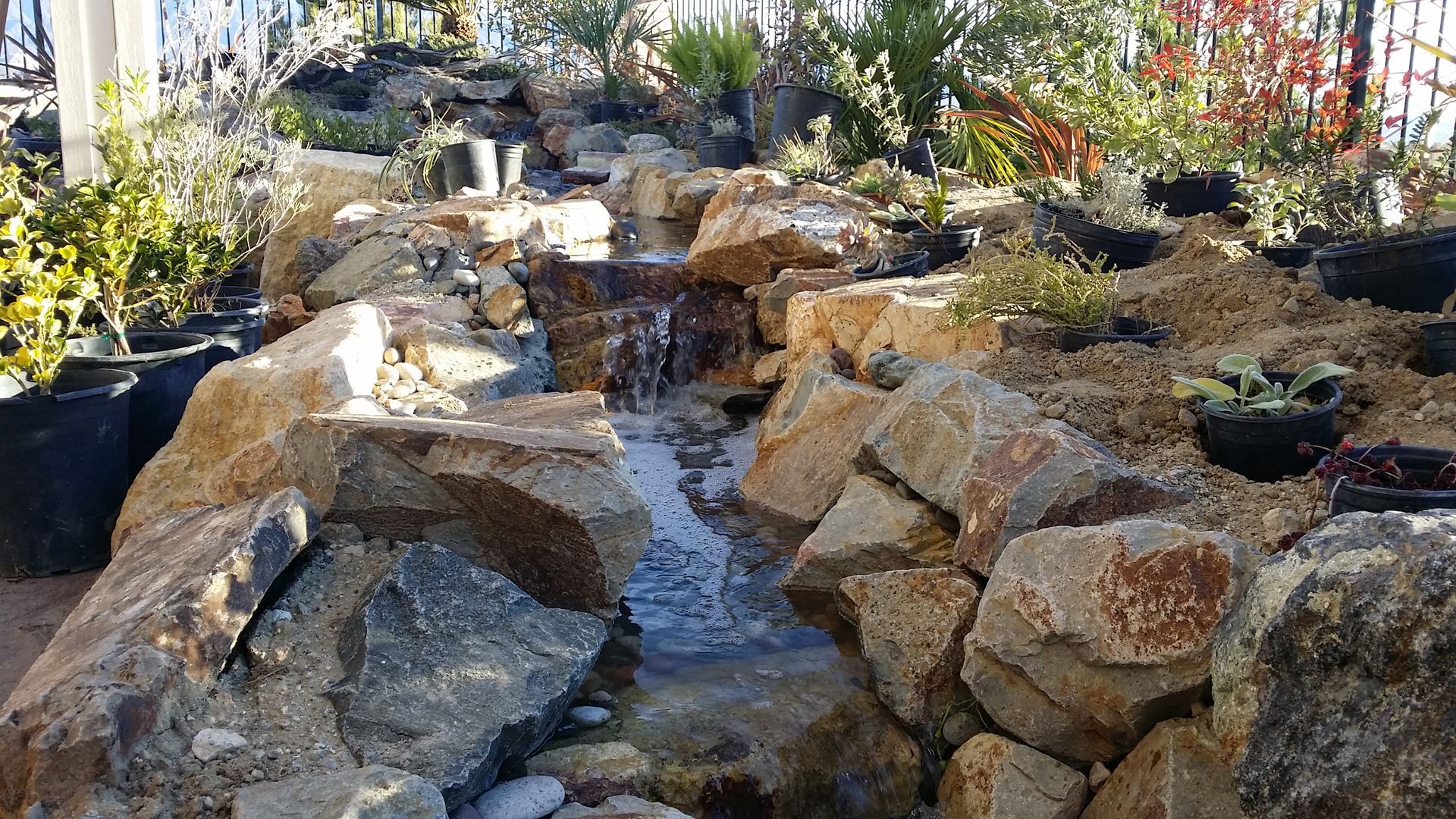 Water flows over rocks in a garden, creating a small waterfall.