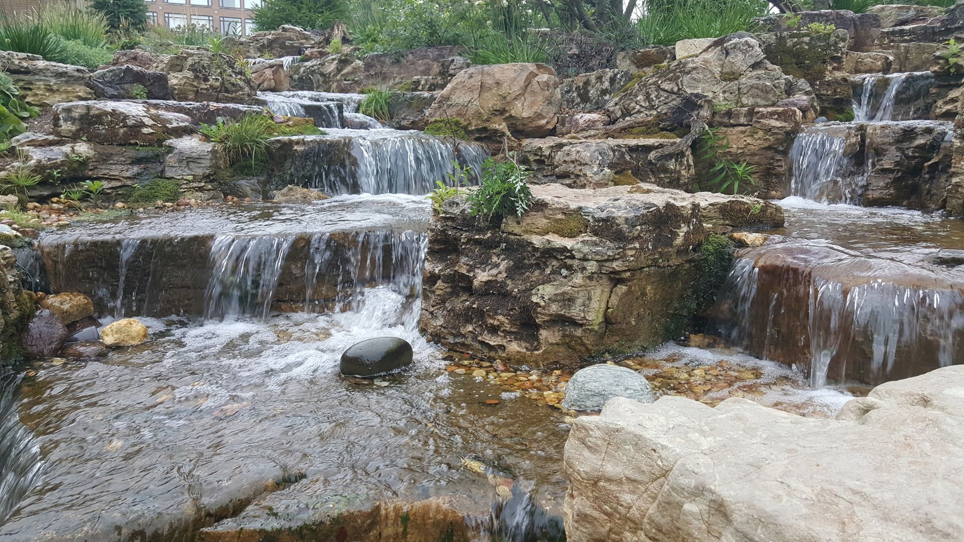Water cascading down tiered stone steps in a naturalistic waterfall setting.