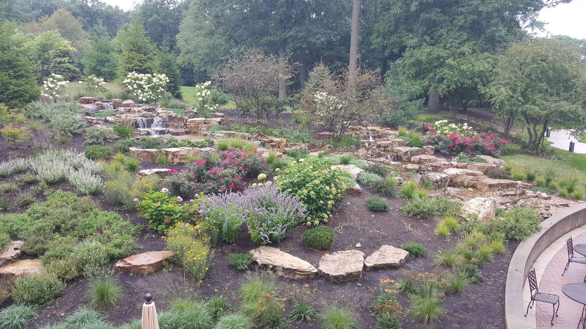 Terraced garden with colorful flowers and small waterfalls.