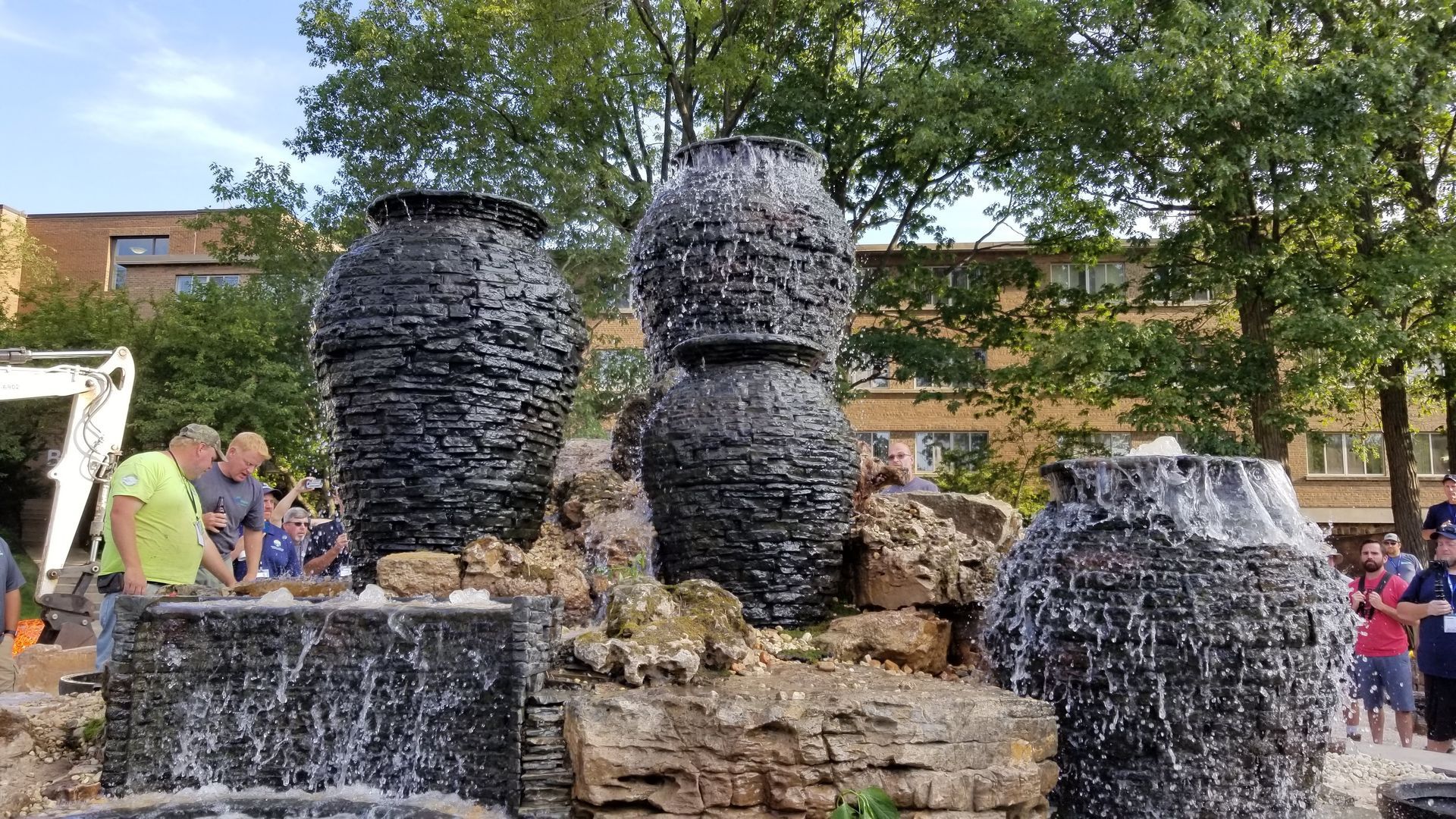 Sculpture of tiered urns with water features, people in background.