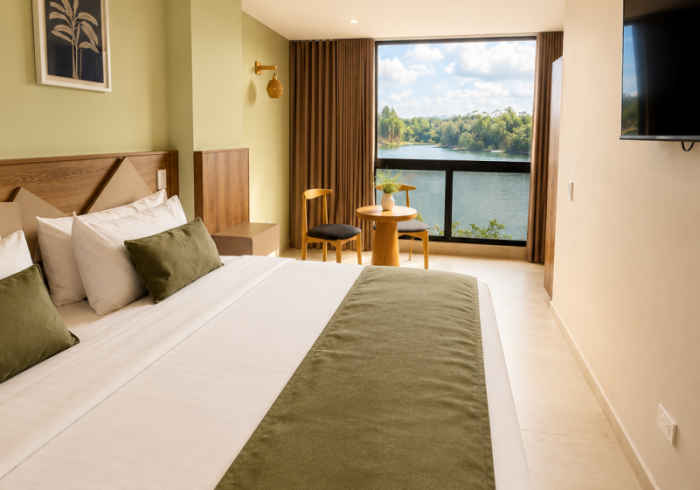 Habitación de hotel moderna con dos camas individuales, balcón con vistas y televisor en la pared.