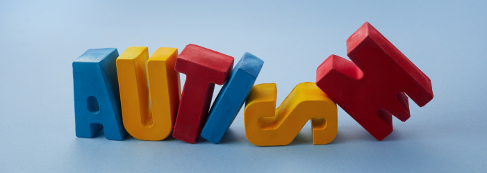 The word autism is written in colorful wooden letters.