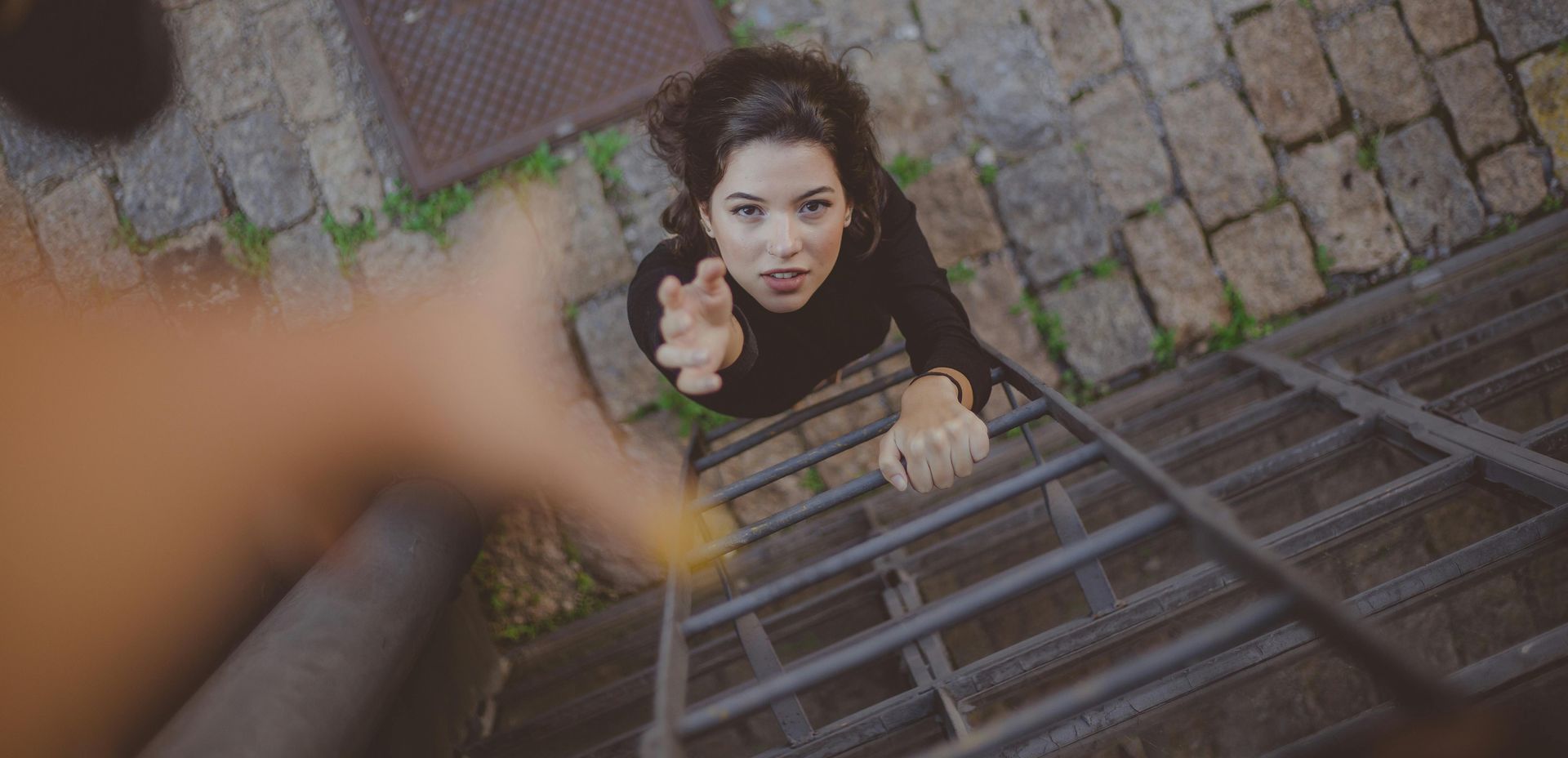 A woman is climbing up a metal ladder.
