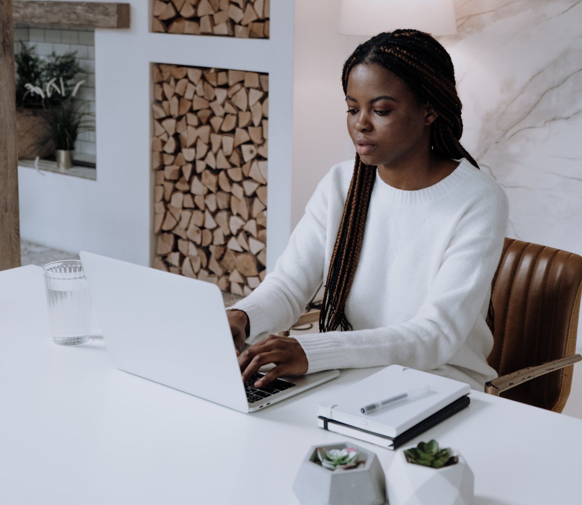 A woman is sitting at a desk using a laptop computer.
