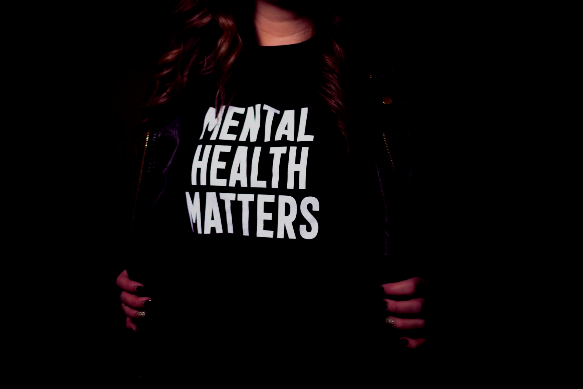 A woman is wearing a black t-shirt that says `` mental health matters ''.