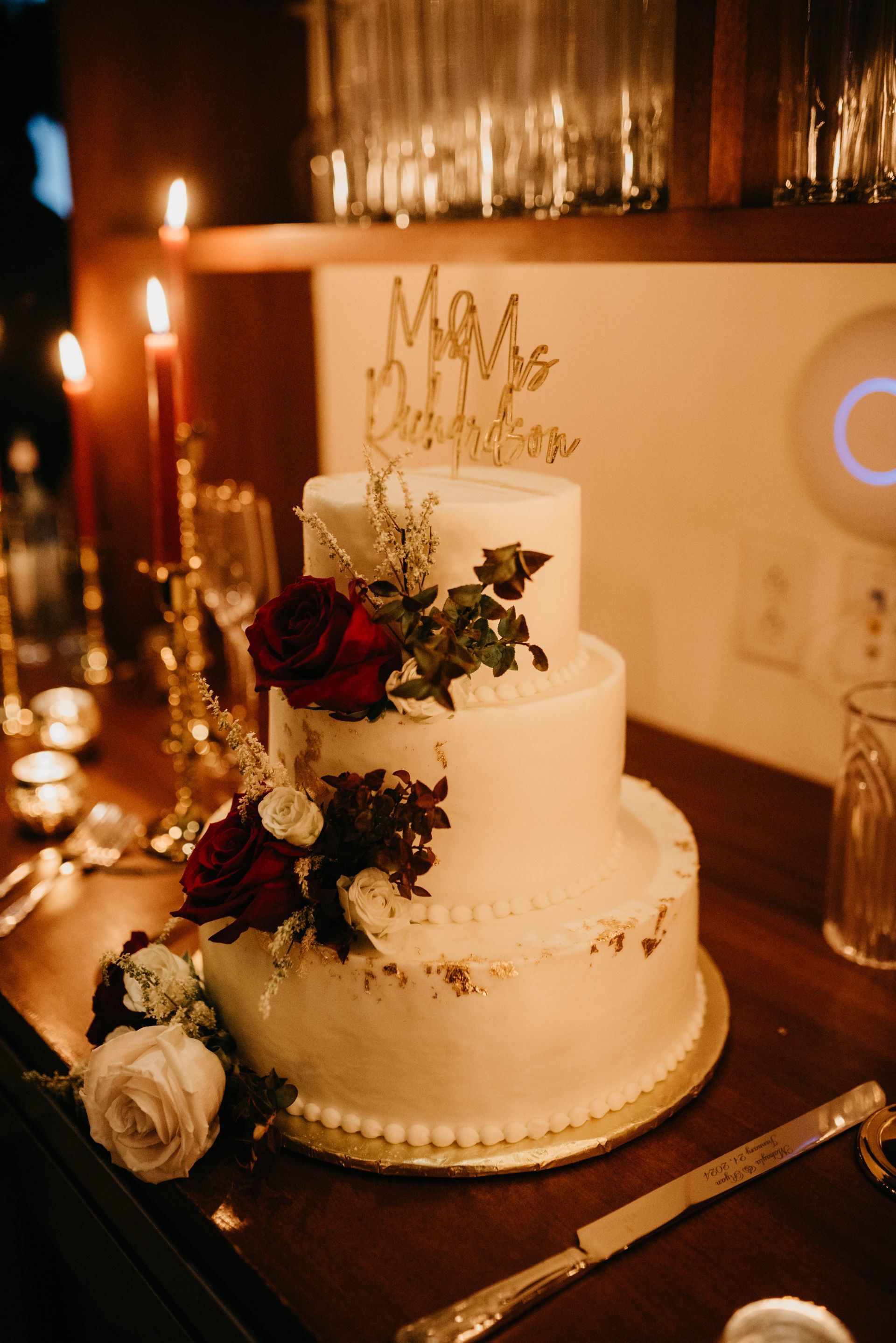 Three-tiered wedding cake with floral accents, topped with gold 